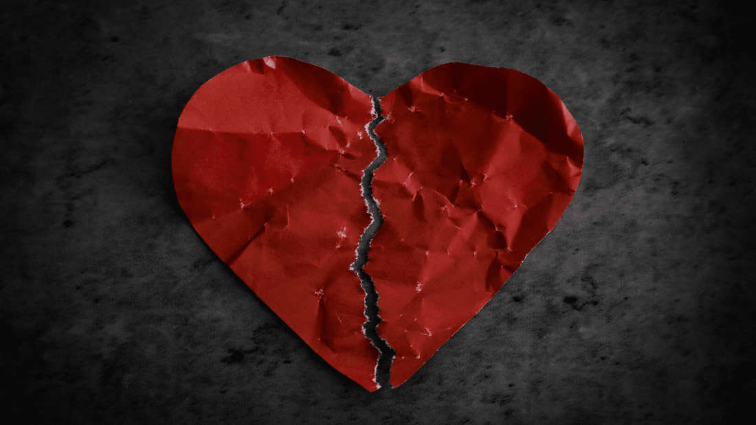 Torn red paper heart symbolizing heartbreak and emotional healing after a breakup.